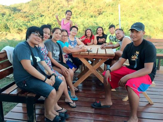 Friends gather around a table outdoors, enjoying each other’s company in a relaxed setting.