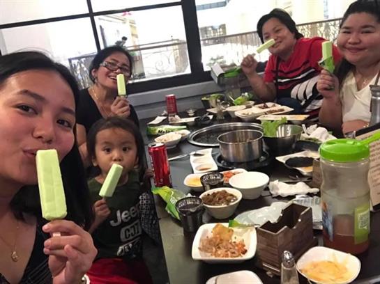 Five people share laughter and ice cream while enjoying a meal at a lively restaurant.