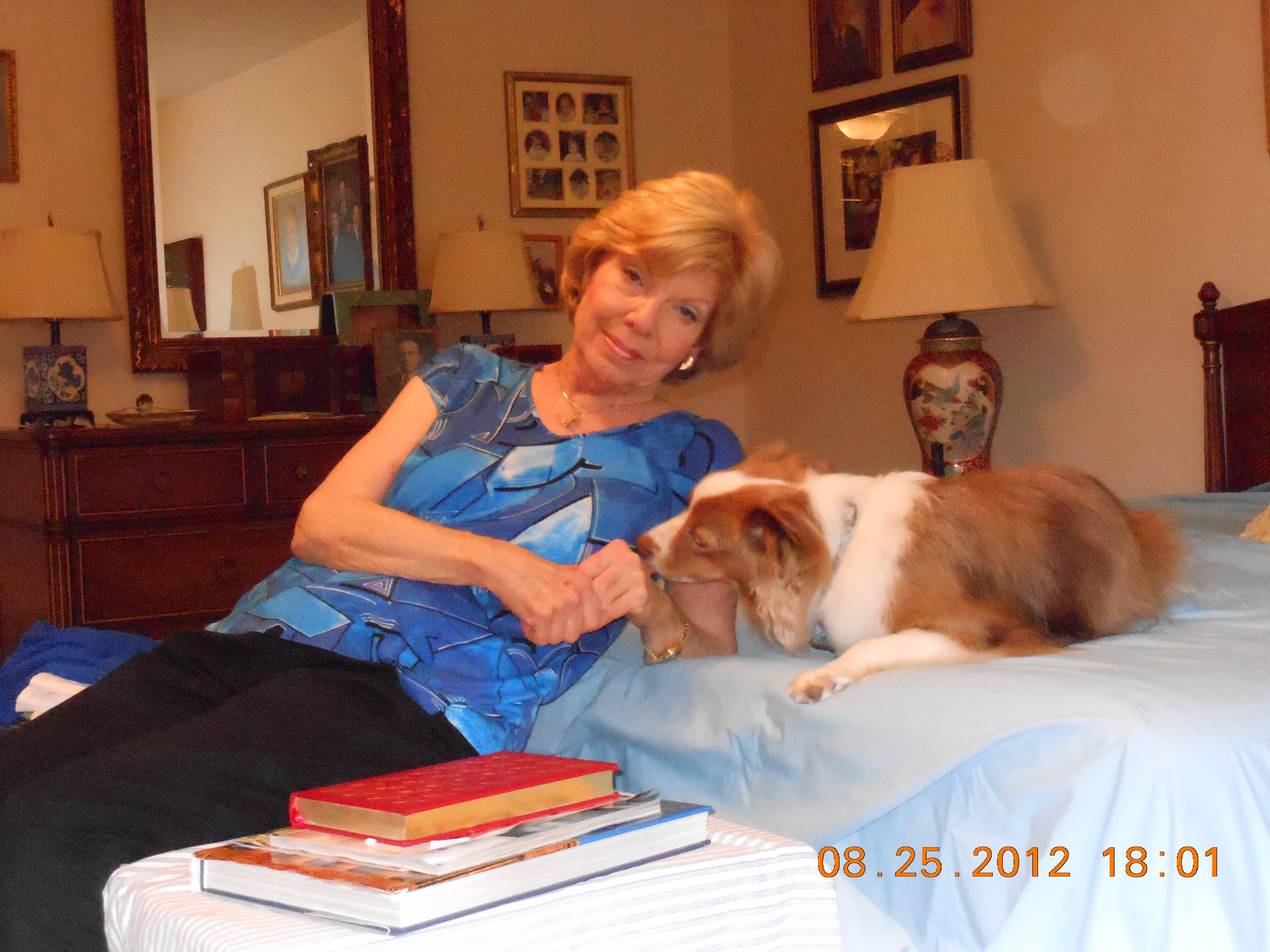 A woman enjoys playful moments with her dog in a warm and inviting bedroom setting.