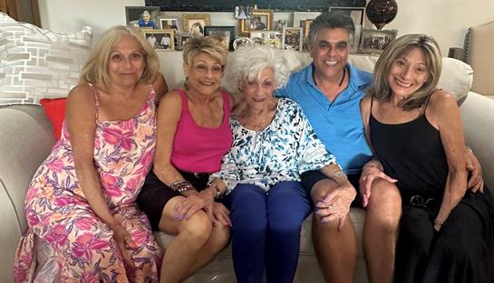 Five friends laugh and share memories together on a cozy couch.