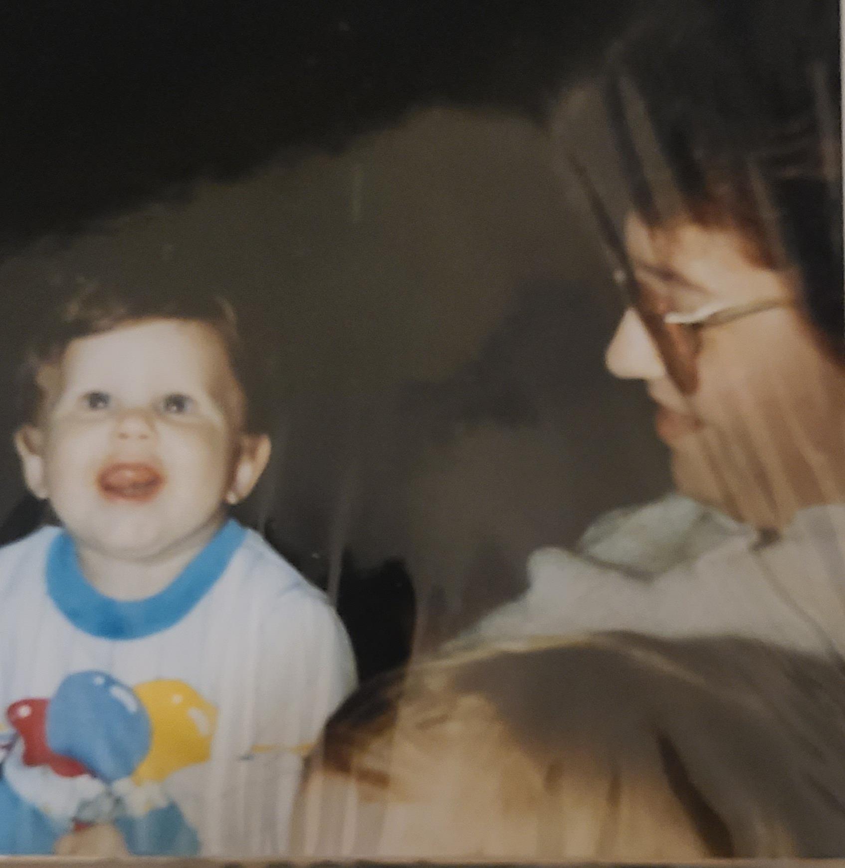 A grandparent shares a joyful moment with a smiling toddler indoors, creating a warm atmosphere.