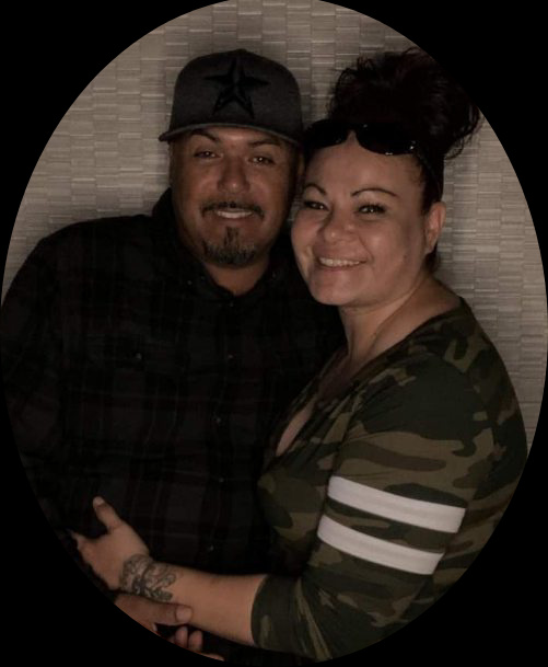 A couple stands close together smiling while enjoying each other's company at a social gathering.
