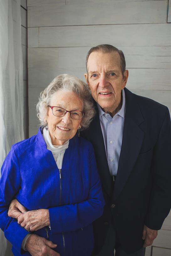A joyful elderly couple smiles together, showcasing their deep bond in a bright room.