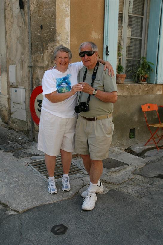 A joyful couple poses with smiles, capturing a memorable moment on a sunny street.