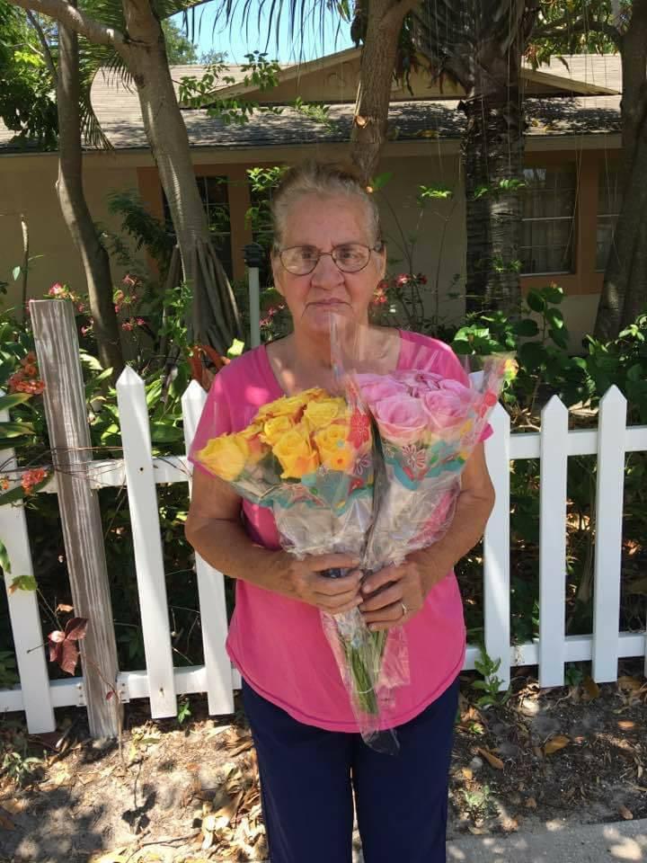 A woman holding flowers in front of a house