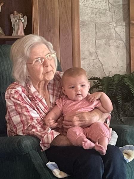A grandmother lovingly embraces her infant granddaughter in a warm living room setting.