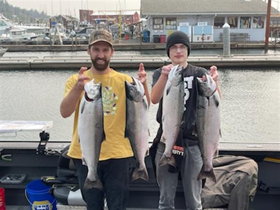 Two men holding fish posing for the camera