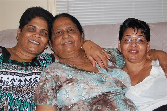 Three women sit closely together, smiling and enjoying each other's company in a warm atmosphere.