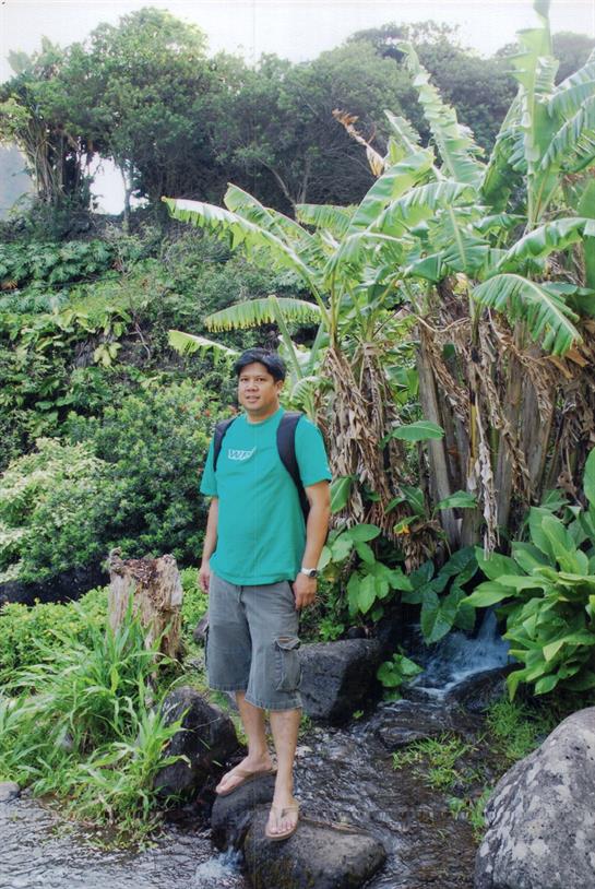 A man enjoys a moment in a vibrant tropical landscape filled with greenery.