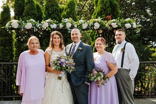 A joyful gathering showcases the bride and groom standing proudly with their family in a garden.