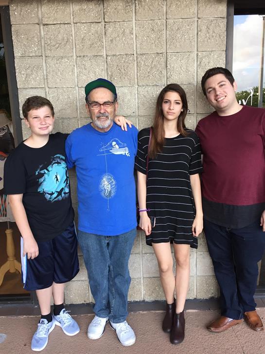 Four individuals stand closely together, smiling at the camera outside a building.