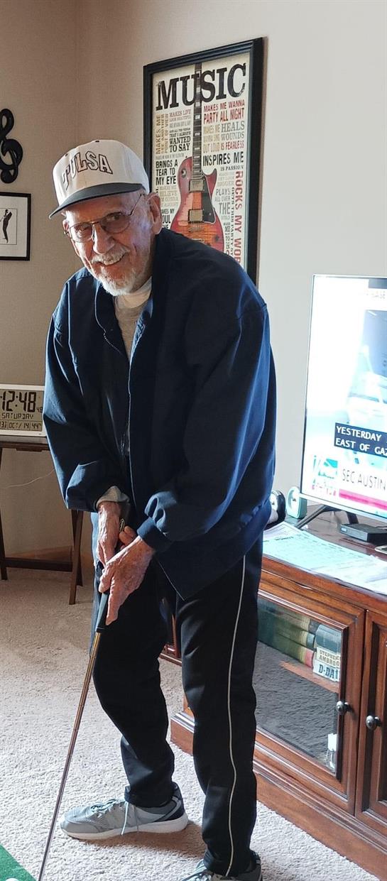 A senior man is having fun playing mini golf indoors, engaging in a leisurely activity.
