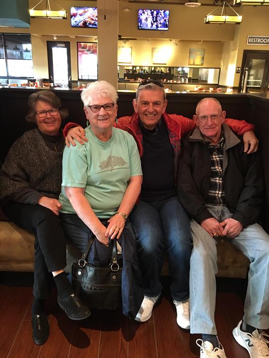 Four friends relax together in a restaurant, smiling and enjoying each other's company.