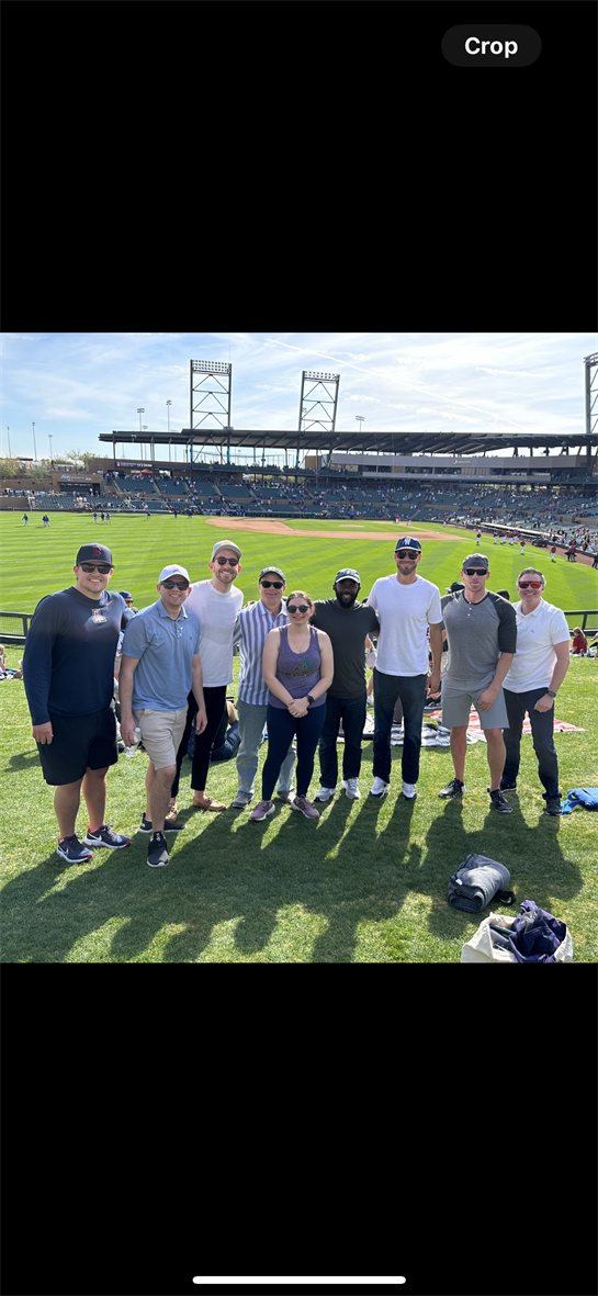 Friends gather together on a sunny day at a baseball stadium to enjoy the game.