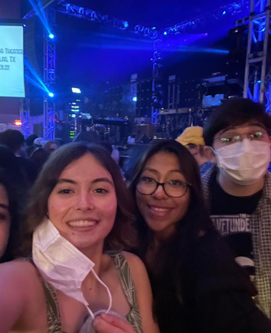 Friends gather for a lively music event under colorful lights, capturing a joyful moment together.