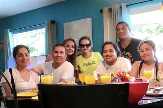 Group of friends sharing a joyful brunch together in a bright kitchen while smiling and chatting.