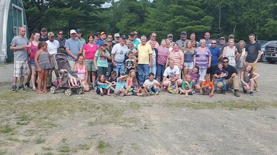 Large group of family and friends gathered for a summer reunion in a scenic park setting.