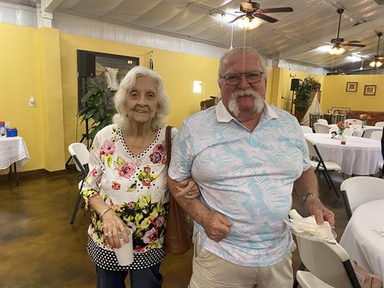 Two seniors share a heartwarming moment while attending a community event indoors.