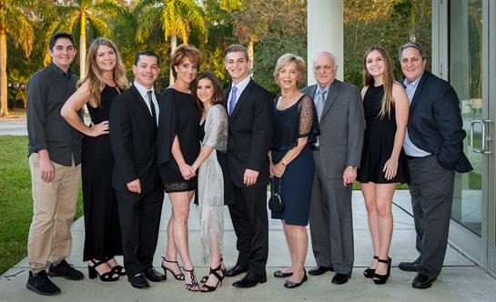 A group of people dressed in formal outfits gather outside for a celebration during the evening.