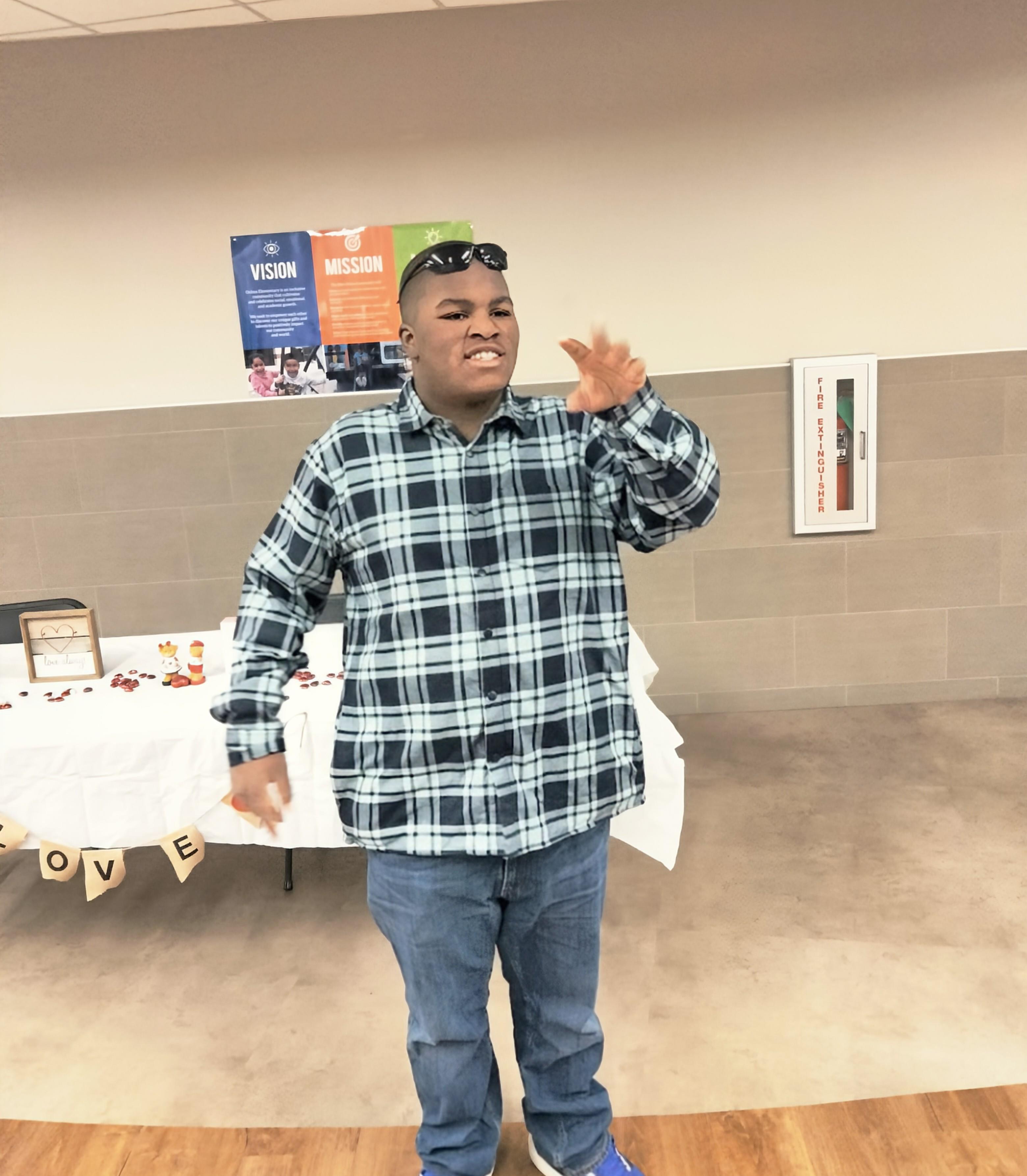 A person in a plaid shirt and sunglasses shares thoughts at a community gathering.