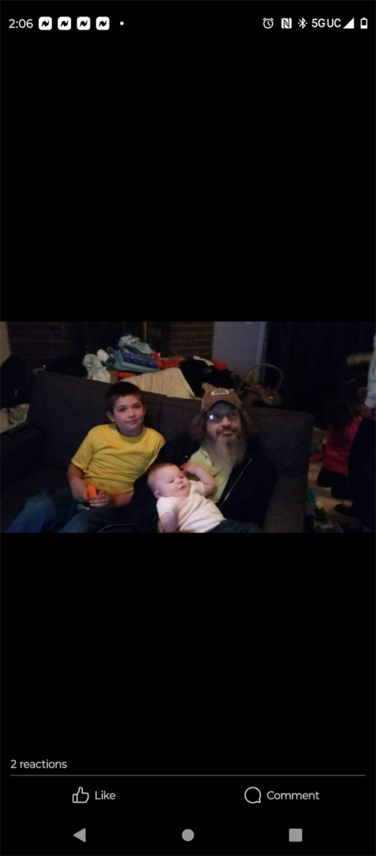 Two children and an elderly man sit together on a couch in a relaxed atmosphere.