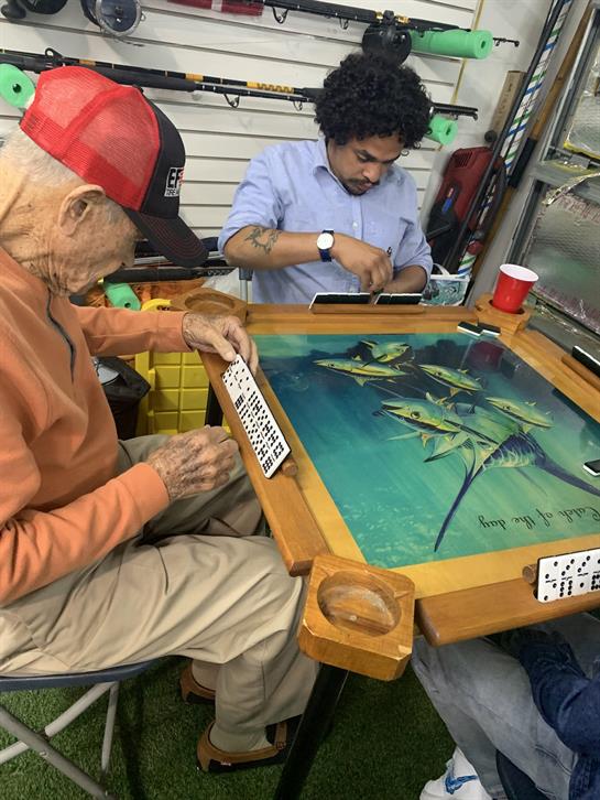 Two individuals, one elderly and one young, are playing a board game together indoors.