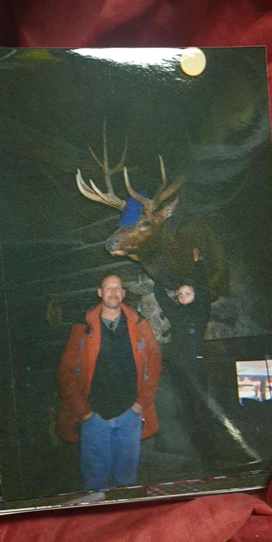 A family enjoys their time at a wildlife exhibit with a large mounted deer on display.