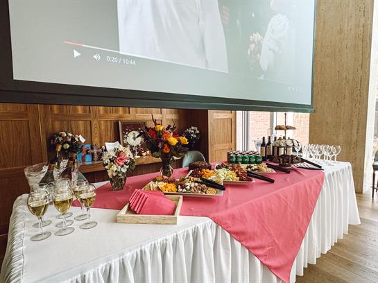 A beautifully arranged dessert table with floral decorations and a large screen backdrop.