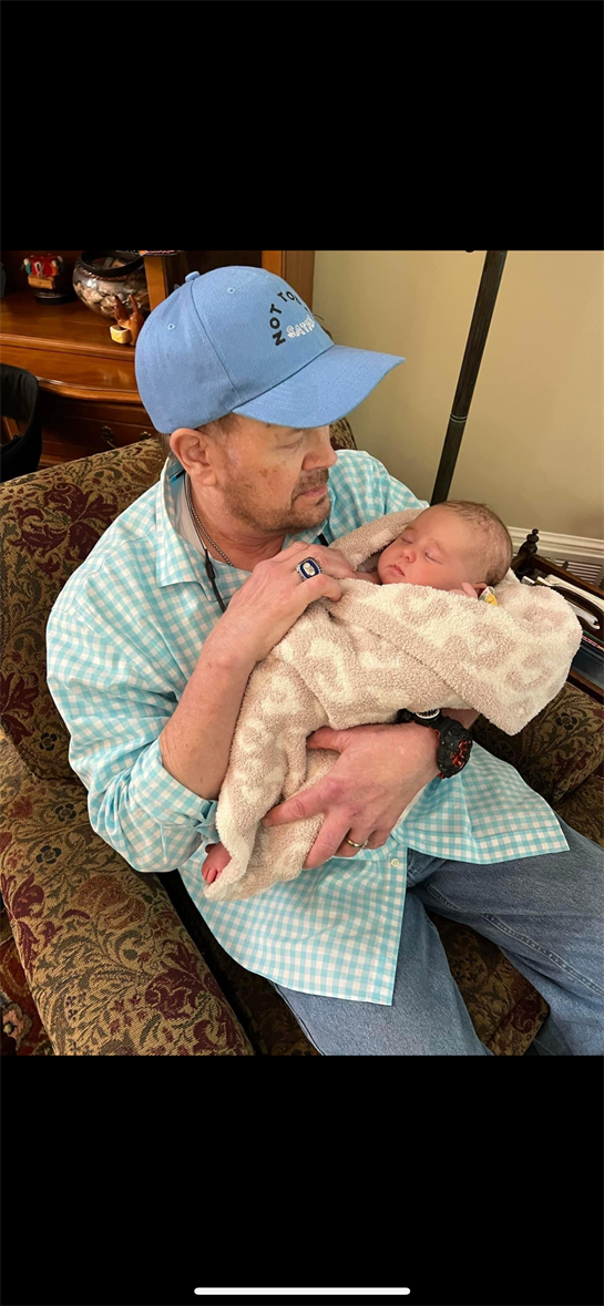 A grandfather cradles his sleeping grandchild, providing warmth and affection in a cozy room.