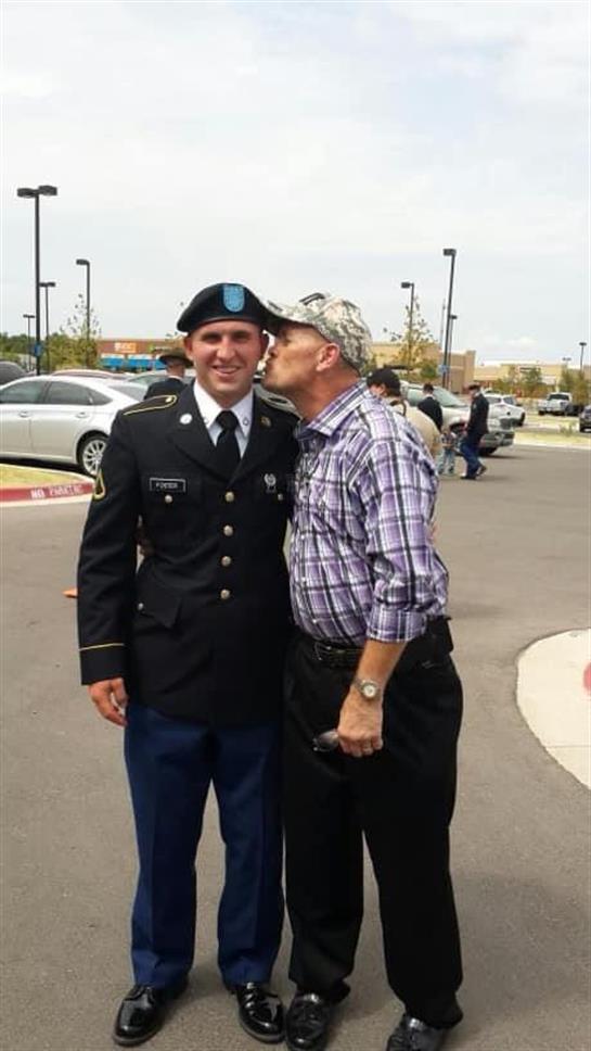 A soldier in uniform shares a heartfelt moment with his grandfather, who greets him with a kiss.