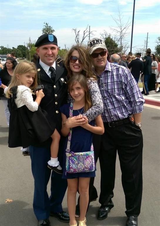 Soldier in uniform embraces family during emotional reunion at homecoming event.