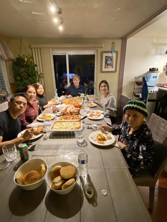 A group of family members shares a hearty meal, filled with various dishes, in a cozy setting.