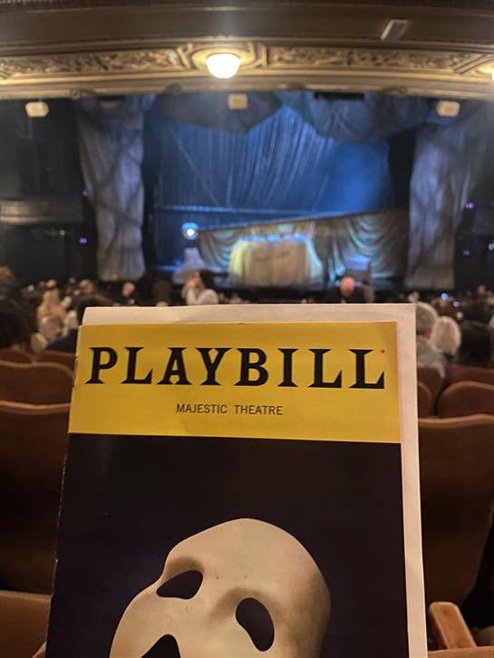 Audience members at the Majestic Theatre eagerly await the show, clutching playbills.