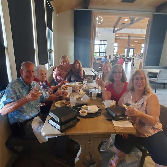 A group of friends enjoy drinks and food, sharing laughter at a restaurant table.