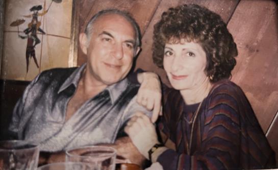 A couple relaxes at a restaurant, engaging in warm conversation and laughter over drinks.