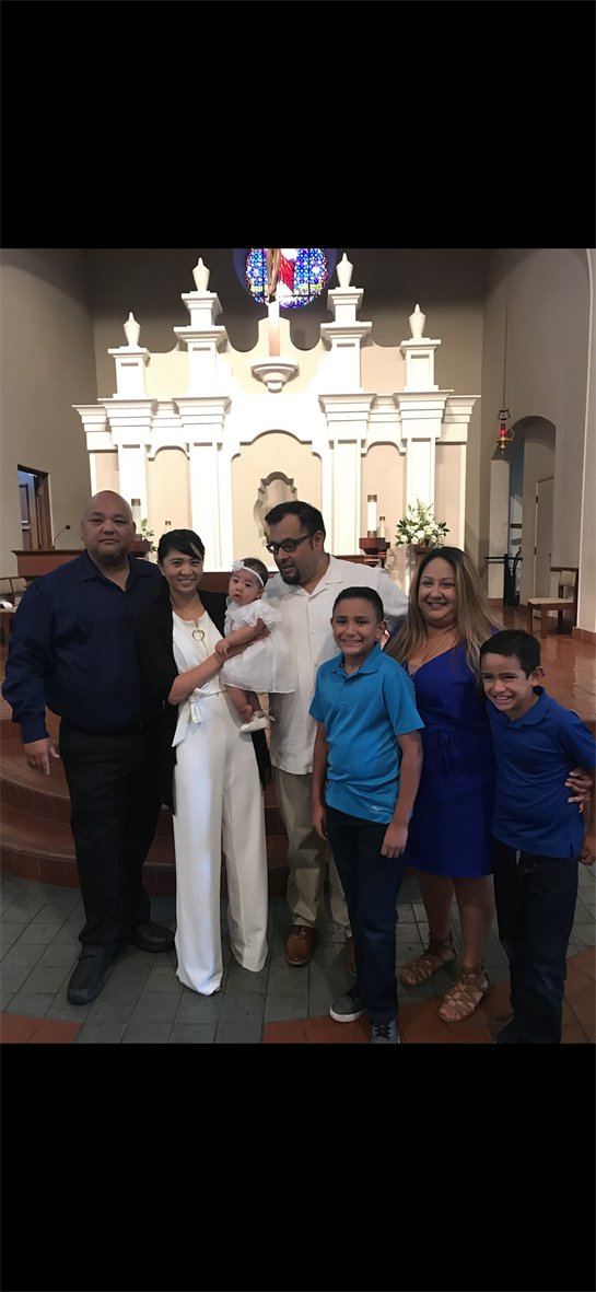 Family members pose together inside a church, celebrating a significant event with a newborn.