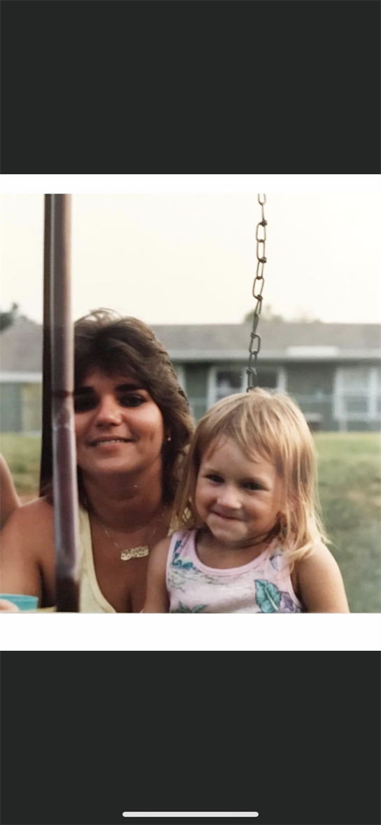 A joyful moment captures a mother and daughter smiling together on a swing while enjoying summer.