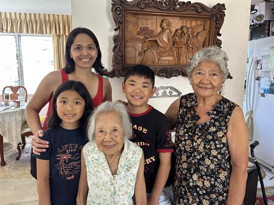 Five family members pose happily in a cozy living room filled with love and warmth.