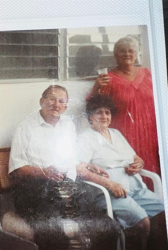 Three friends relax together on a porch, sharing drinks and enjoying each other's company.