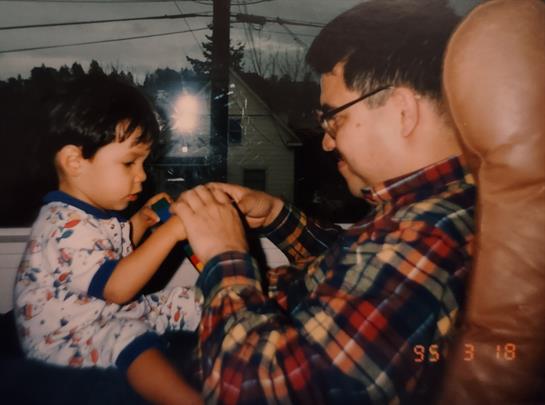 A young boy in pajamas shares a playful moment with his grandfather indoors.