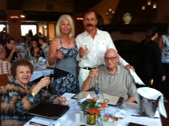 Four friends raise glasses in celebration at a restaurant during dinner time.