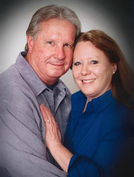 A man and woman share a warm embrace, smiling happily at the camera, showcasing their love.