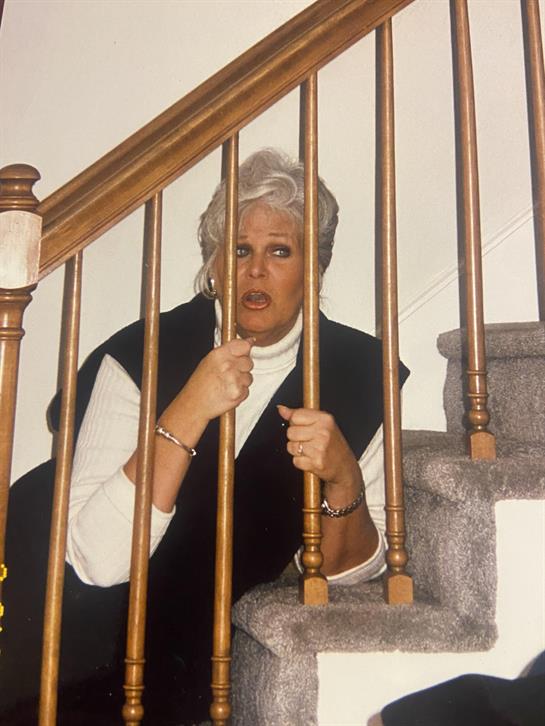 A woman appears startled while sitting on the stairs, holding onto the railing tightly.