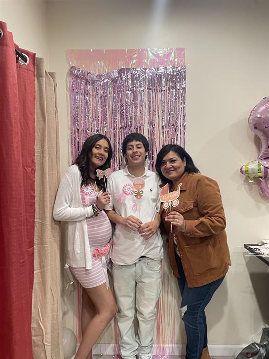 Family members gather together to celebrate an upcoming baby, holding fun props and smiling.