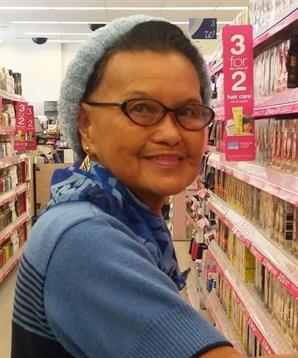 Woman with glasses enjoys shopping for cosmetics in an active retail store.