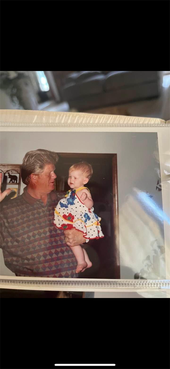 A grandfather holds his laughing granddaughter while they share a loving moment in a cozy home.