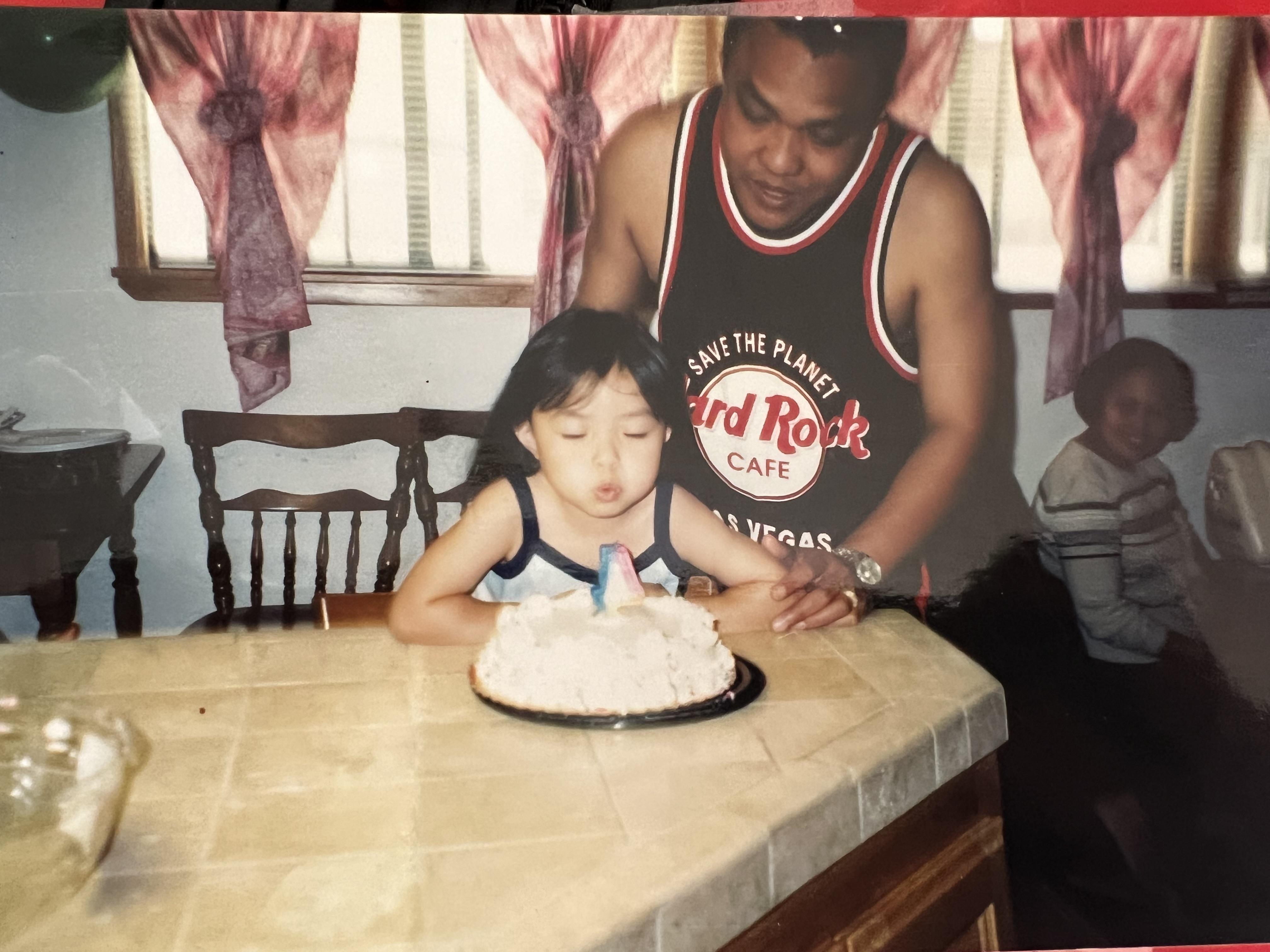 Young girl makes a wish and blows out candles on her birthday cake with family nearby.