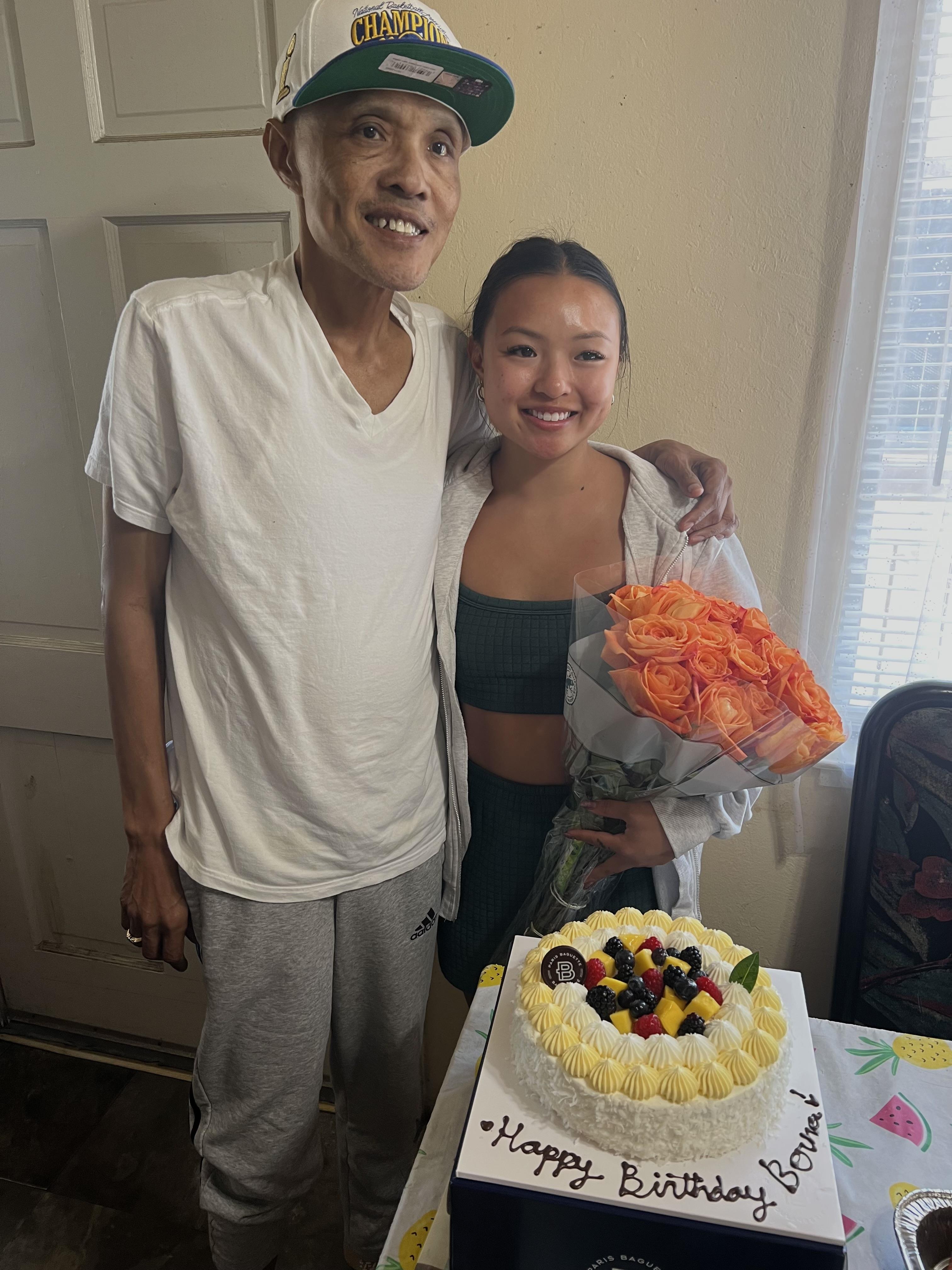 A young woman and her father celebrate her birthday with gifts and a lovely cake.