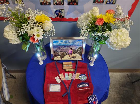 Colorful flowers and a photo honor community service on a blue table with a red vest.