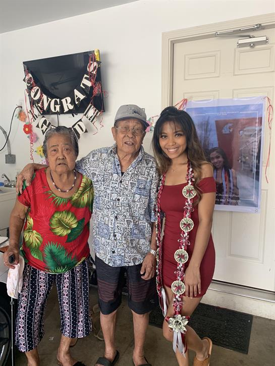 Three family members proudly pose together during a festive celebration at home.
